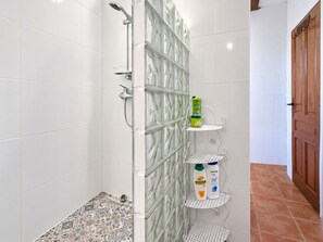 Ein Badezimmer mit weißen Fliesen, einer Duschkabine aus Glas und einem gefliesten Boden.