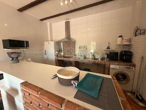 A kitchen with a microwave, stove, sink, and a washing machine. - Countryside Escape Just Minutes from the Coast (Mijas)