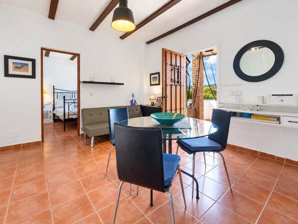A dining area with a glass table, four chairs, a bowl, and a hanging light fixture. - Countryside Escape Just Minutes from the Coast (Mijas)