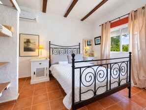 Ein Schlafzimmer mit einem Bett, Nachttischen, einem Kleiderschrank und einem Fenster mit Vorhängen.