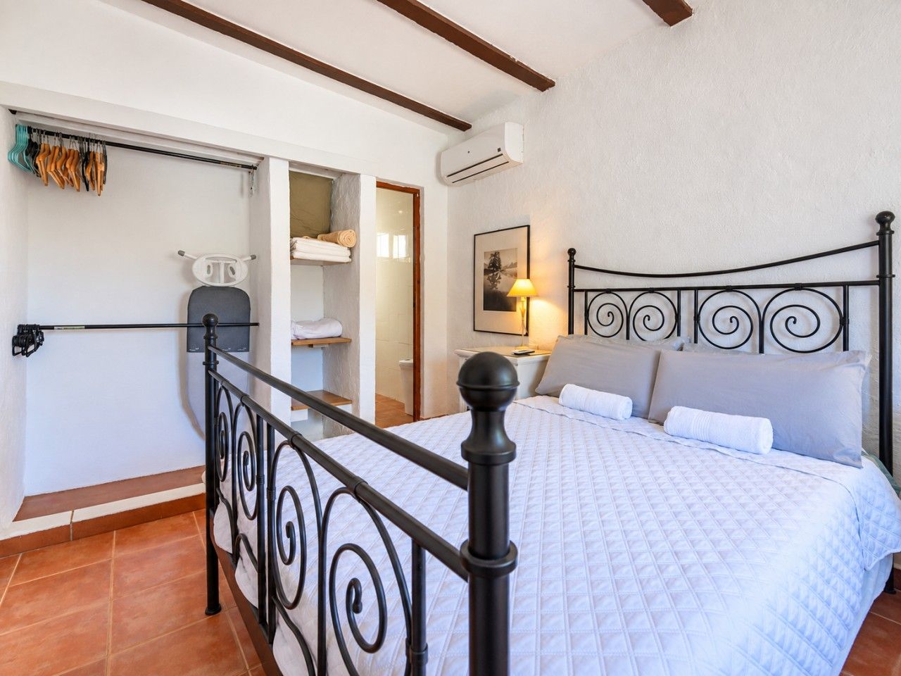 A bedroom with a bed, a nightstand, a lamp, and a wardrobe.