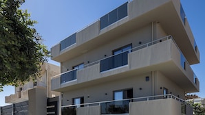 A multi-story building with balconies, a gated entrance, and a landscaped area with planters.