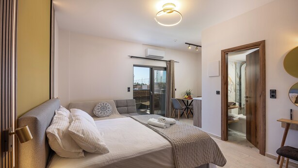 A modern hotel room with a large bed, a desk, and a view through a glass door.