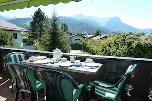 Eine Terrasse mit Tisch, Stühlen und Blick auf die Berge.