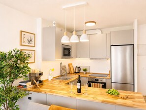 Eine moderne Küche mit Holzarbeitsplatte, Edelstahlgeräten, Pendelleuchten und einem Blumentopf.