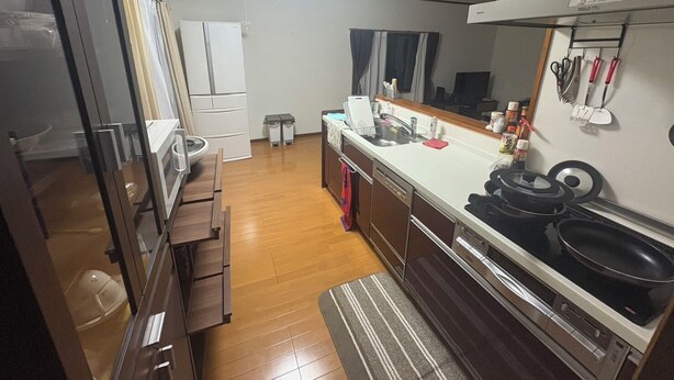 Une cuisine de taille réduite, équipée d’un réfrigérateur, d’une cuisinière, d’un évier et de meubles de rangement en bois.