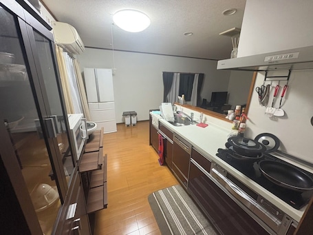A compact kitchen with a refrigerator, stove, sink, and wooden cabinets.. Private, unreserved lodgings with sunken hearths, limited to one couple per day (pets are allowed!)