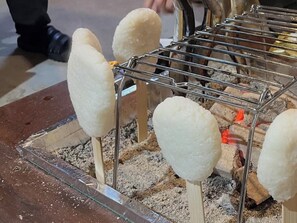 A metal rack with several white objects on sticks, possibly food items, over a fire.