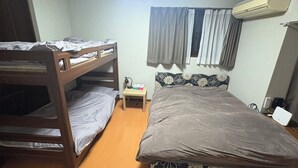 Une chambre avec des lits superposés, une petite table de chevet avec une lampe et un appareil de climatisation.