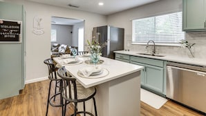 Una cocina moderna con una isla central, taburetes de bar, un refrigerador y un lavavajillas.