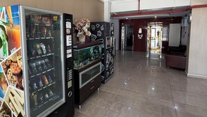 Un vestíbulo de hotel con máquinas expendedoras, una recepción y una vista despejada a la entrada.