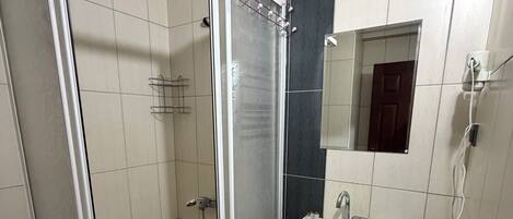Un baño con ducha de vidrio, lavamanos blanco y retrete.