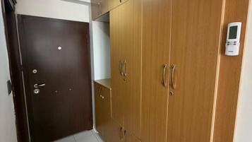 Un pasillo con un armario de madera, una puerta y un accesorio de iluminación.