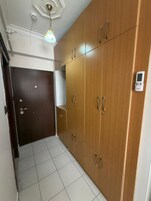 Un pasillo con un armario de madera, una puerta y un accesorio de iluminación.