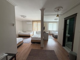 A hotel room with two beds, a small kitchenette, a mirror, and a view of the outside.