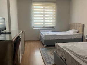 A bedroom with a bed, a desk, a radiator, and a window with blinds. - korkmaz rezidans  (melikgazi)