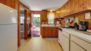 Eine Küche mit Holzausstattung, einem weißen Kühlschrank, einem Herd und einem Spülbecken.