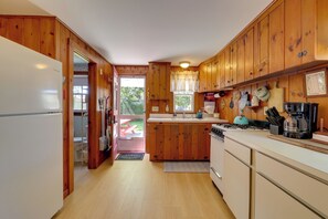 A kitchen with wooden cabinets, a white refrigerator, a stove, and a sink. - Walk to Nantucket Sound Beaches! Family Getaway (Dennis Port)