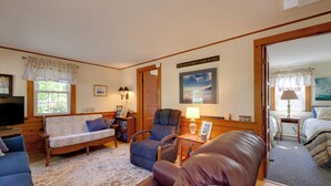 Ein gemütliches Zimmer mit einer Couch, einem Sessel und einem kleinen Tisch mit einer Lampe.