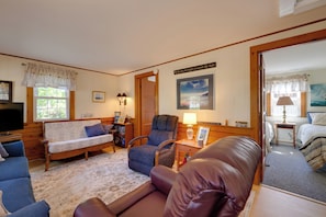 A cozy room with a sofa, armchair, and a small table with a lamp. - Walk to Nantucket Sound Beaches! Family Getaway (Dennis Port)