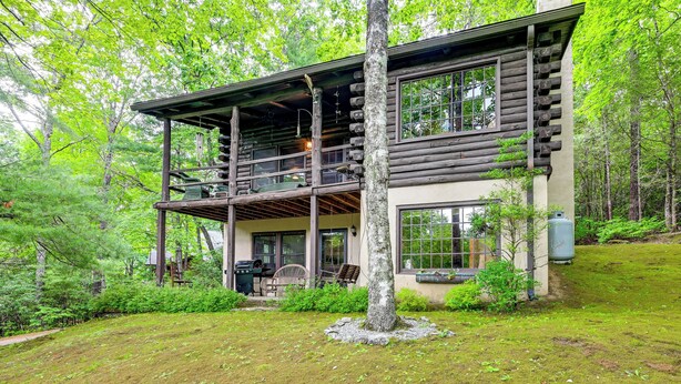 A log cabin with a balcony, surrounded by lush greenery. - Unplug! Lake Toxaway Cabin w/ Dock Access (Lake Toxaway)