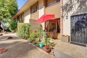 A building with a patio area, a red umbrella, potted plants, and a gated entrance. - Steps to Fashion Square! Condo w/ Patio & Pool (Scottsdale)