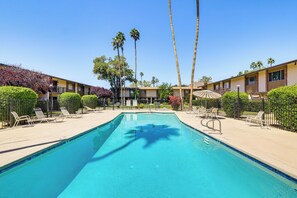 A swimming pool with lounge chairs, palm trees, and a building with a balcony. - Steps to Fashion Square! Condo w/ Patio & Pool (Scottsdale)