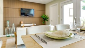 En matplats med ett bord dukat för två personer, en grön tallrik med en vit servett, ett vinglas och en kniv på en underlägg.