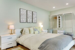 Une chambre à coucher comprenant un lit, des tables de chevet, une armoire et des œuvres d’art murales.
