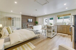 Ein modernes Zimmer mit Bett, Schreibtisch, Stuhl, Kleiderschrank und einer Küchenzeile.