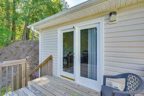 Une maison avec une terrasse en bois, une porte-fenêtre coulissante et une chaise.