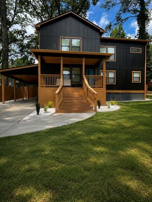 A modern two-story house with a wooden front porch and a covered driveway.