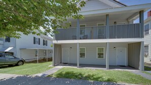 A two-story residential building with a balcony, a covered porch, and a car parked on the street. - Central Hinton Studio Near Dtwn & New River Gorge (Hinton)