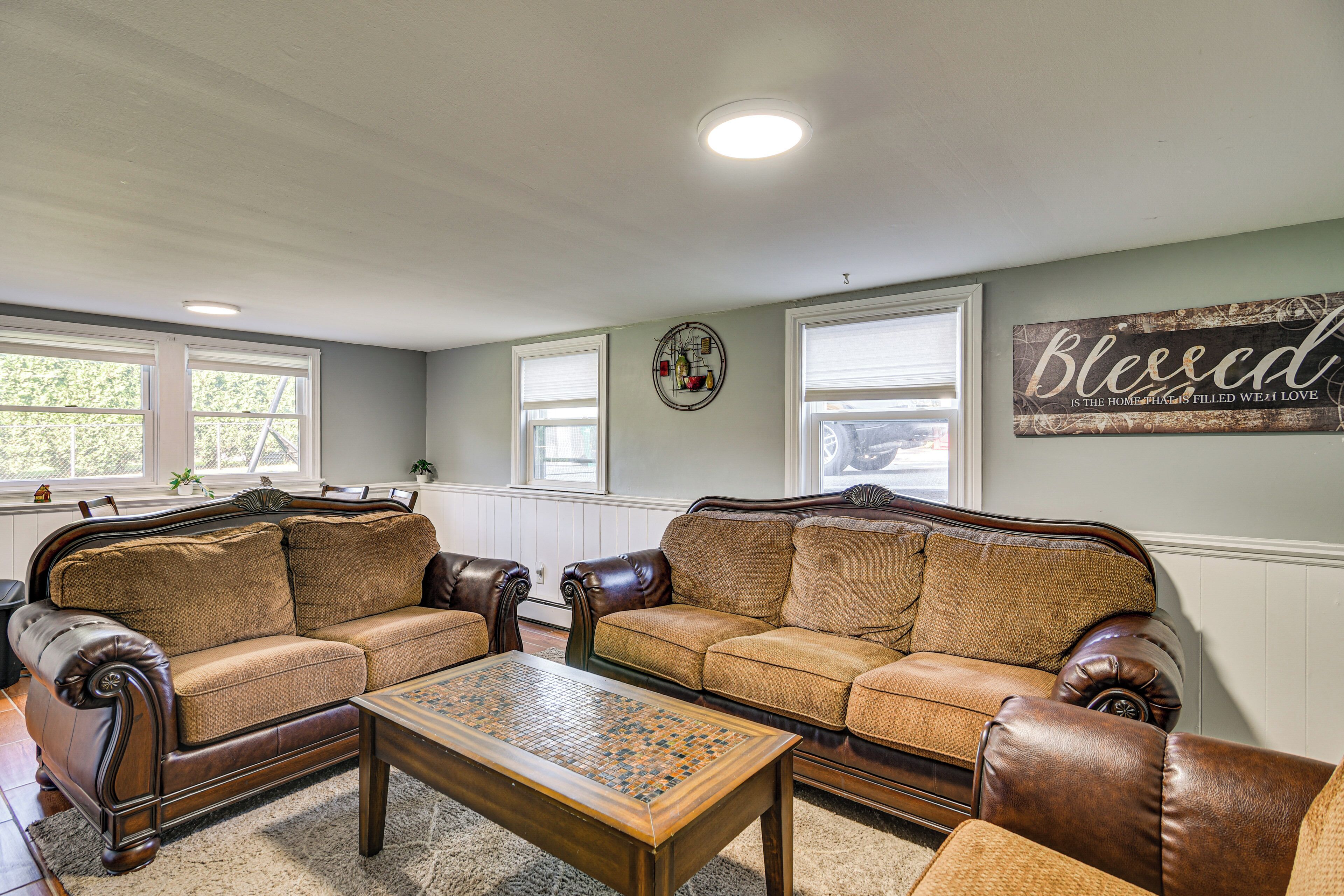 A living room with two leather sofas, a wooden coffee table, and a wall with a decorative sign.