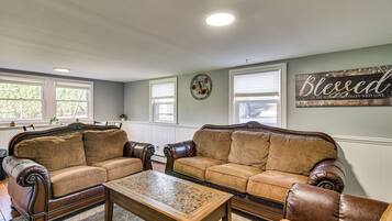 A living room with two leather sofas, a wooden coffee table, and a wall with a decorative sign.