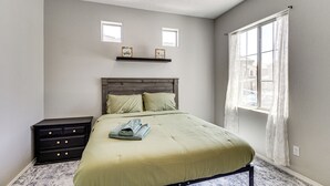 A bedroom with a bed, a nightstand, a window with curtains, and two wall-mounted picture frames. - Suburban Santa Fe Home Near Main Street & I-25 (Los Lunas)