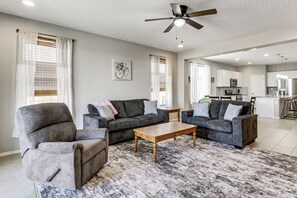 A living room with a sofa, armchairs, a coffee table, and a ceiling fan.
