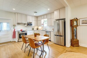 A kitchen with white cabinets, stainless steel appliances, a wooden dining table with chairs, and a grandfather clock. - Upscale Home on 120 Acres: Near Wedding Venues! (Thorndale)