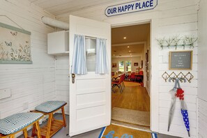 A room with a white door, a bench, a welcome sign, and a wall-mounted umbrella. - Upscale Home on 120 Acres: Near Wedding Venues! (Thorndale)