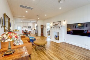 A spacious living room with a fireplace, a television mounted on the wall, and a dining area in the background. - Upscale Home on 120 Acres: Near Wedding Venues! (Thorndale)