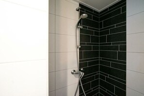 A corner shower with black and white tiles, a handheld showerhead, and a wall-mounted control. - Holiday home in Lochem with terrace (Lochem)