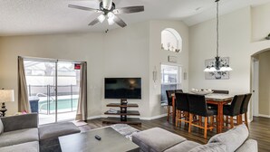 A living room with a sofa, coffee table, TV, and dining area with chairs and a table. - Private Pool! Family-Friendly Southern Dunes Home (Haines City)