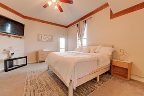 Ein Schlafzimmer mit Bett, Nachttisch, Fernseher und Deckenventilator.