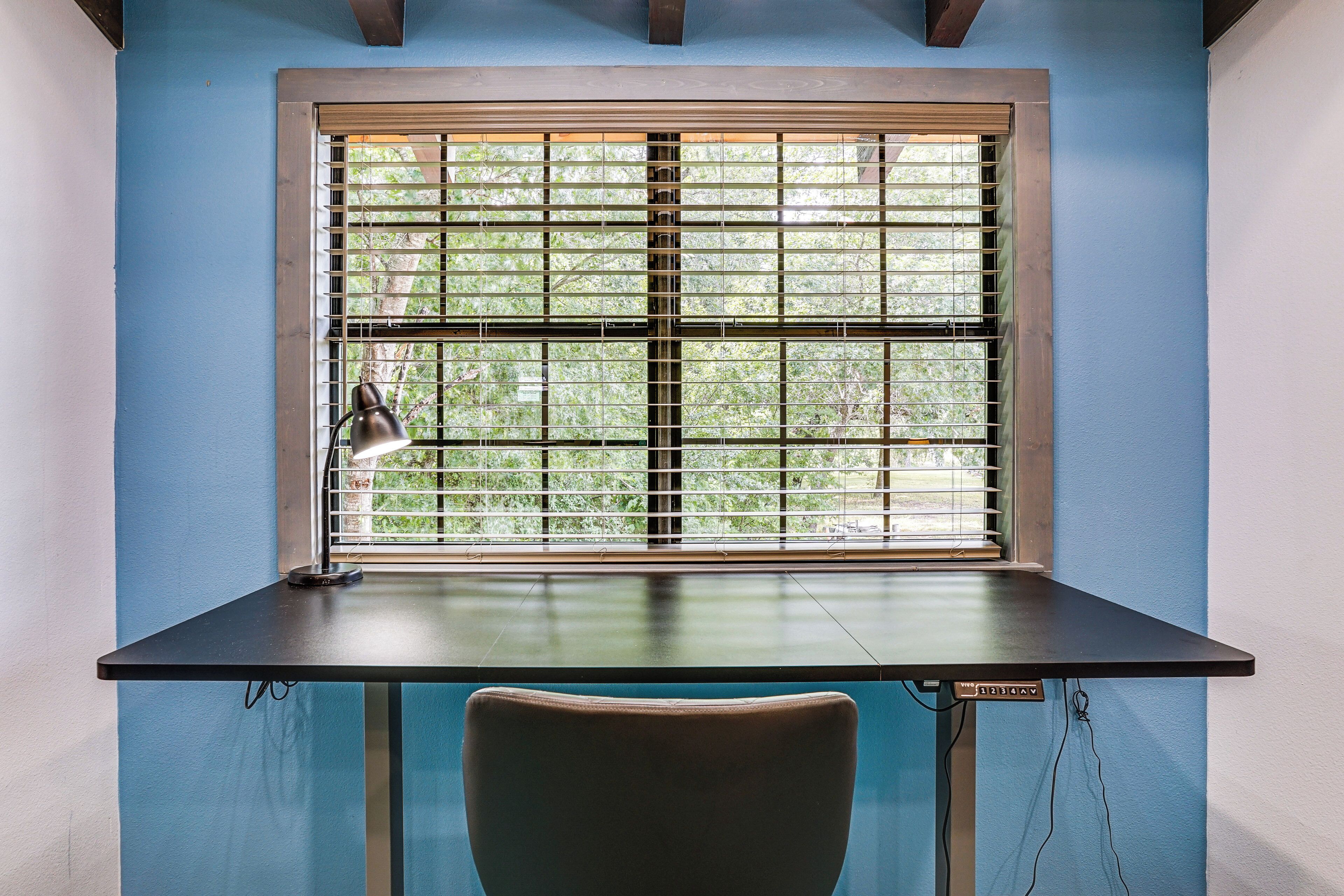 A desk with a lamp, a chair, and a window with blinds.