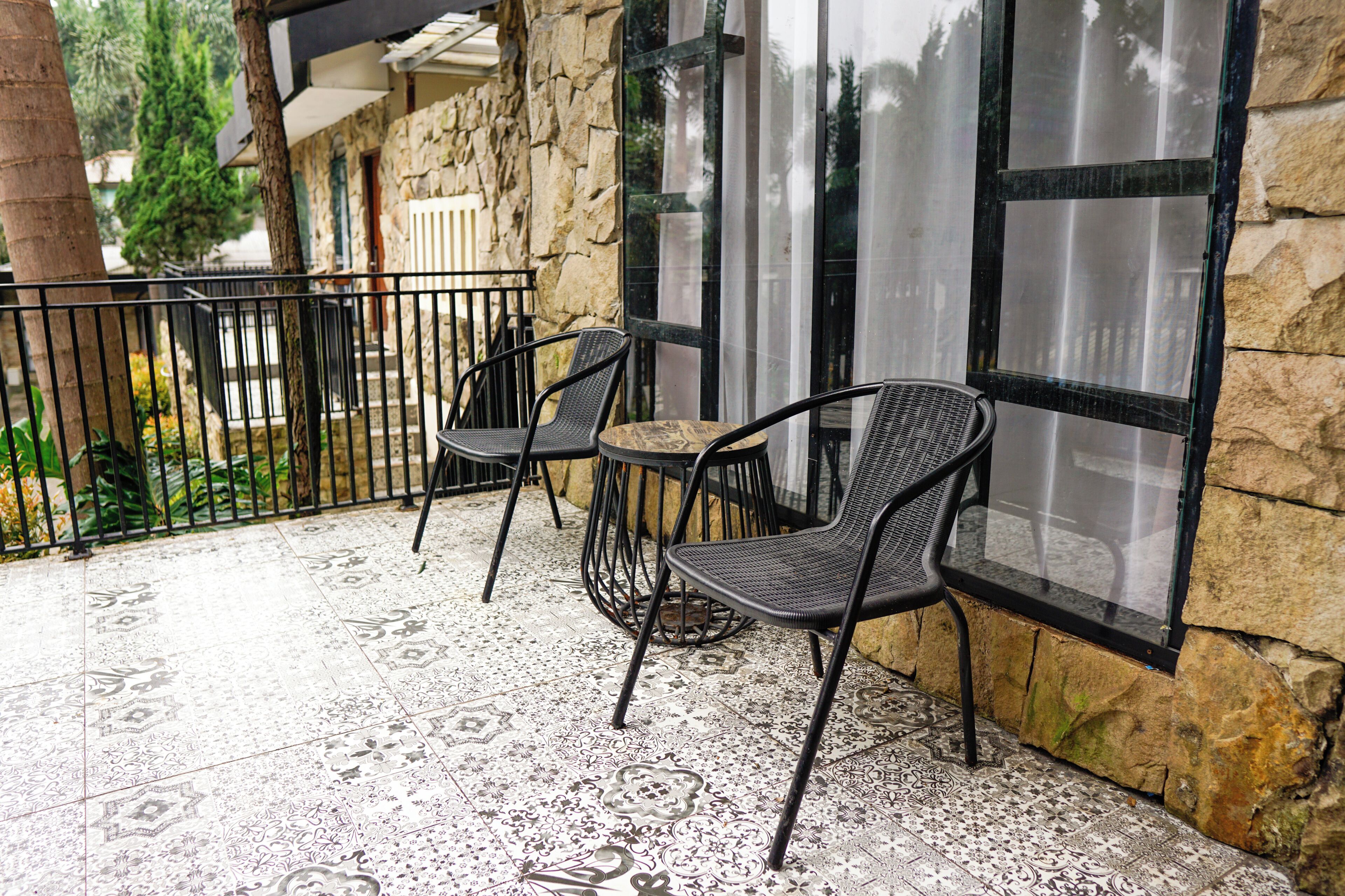 A balcony with patterned floor tiles, a stone wall, and a glass door.