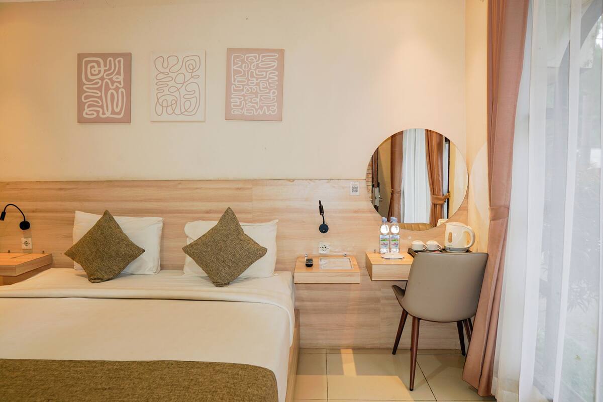 A hotel room with a bed, bedside table, lamp, chair, and artwork on the wall.