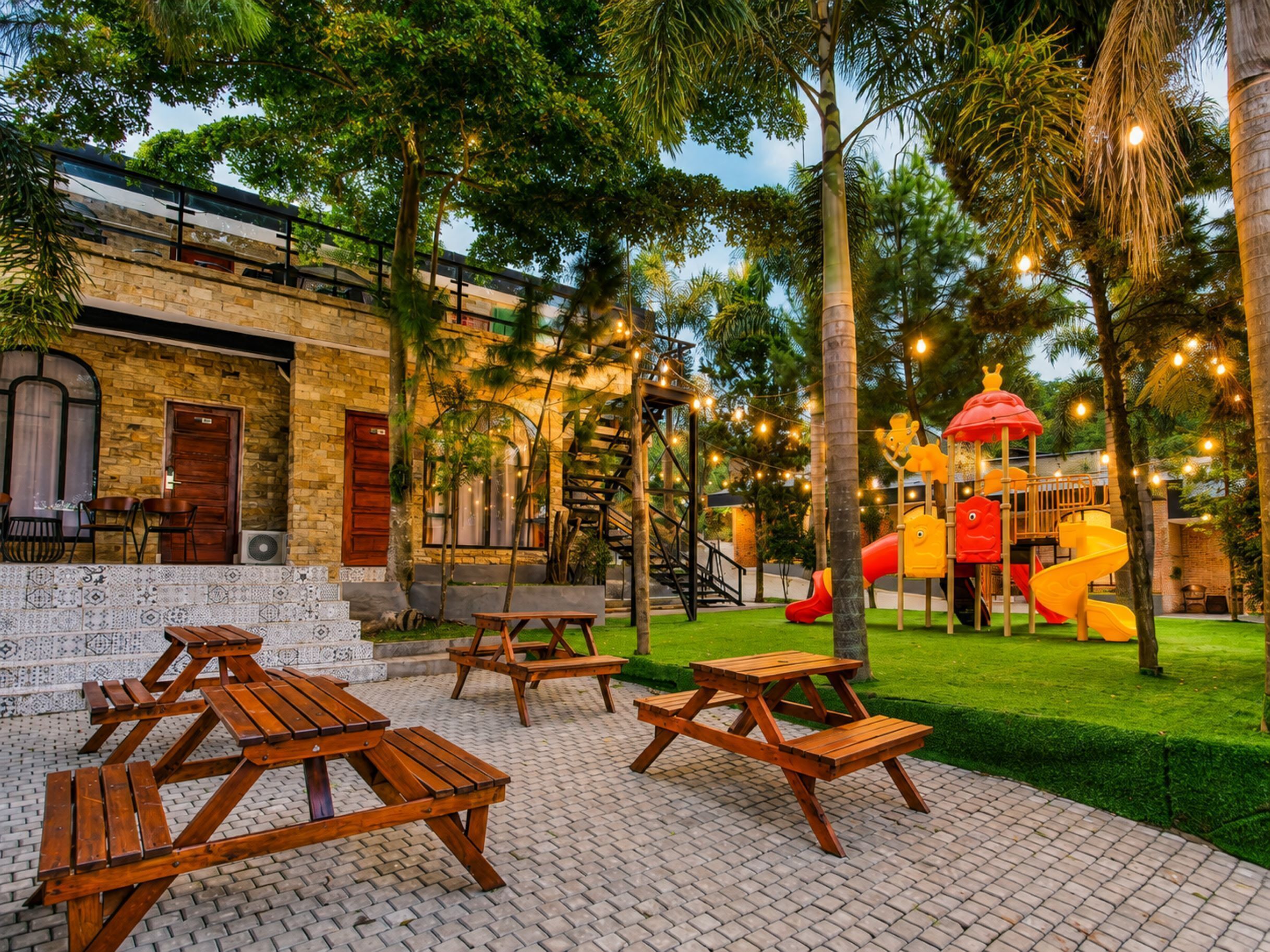 Un patio con mesas de picnic, un área de juegos con toboganes y un edificio de fachada de ladrillo.