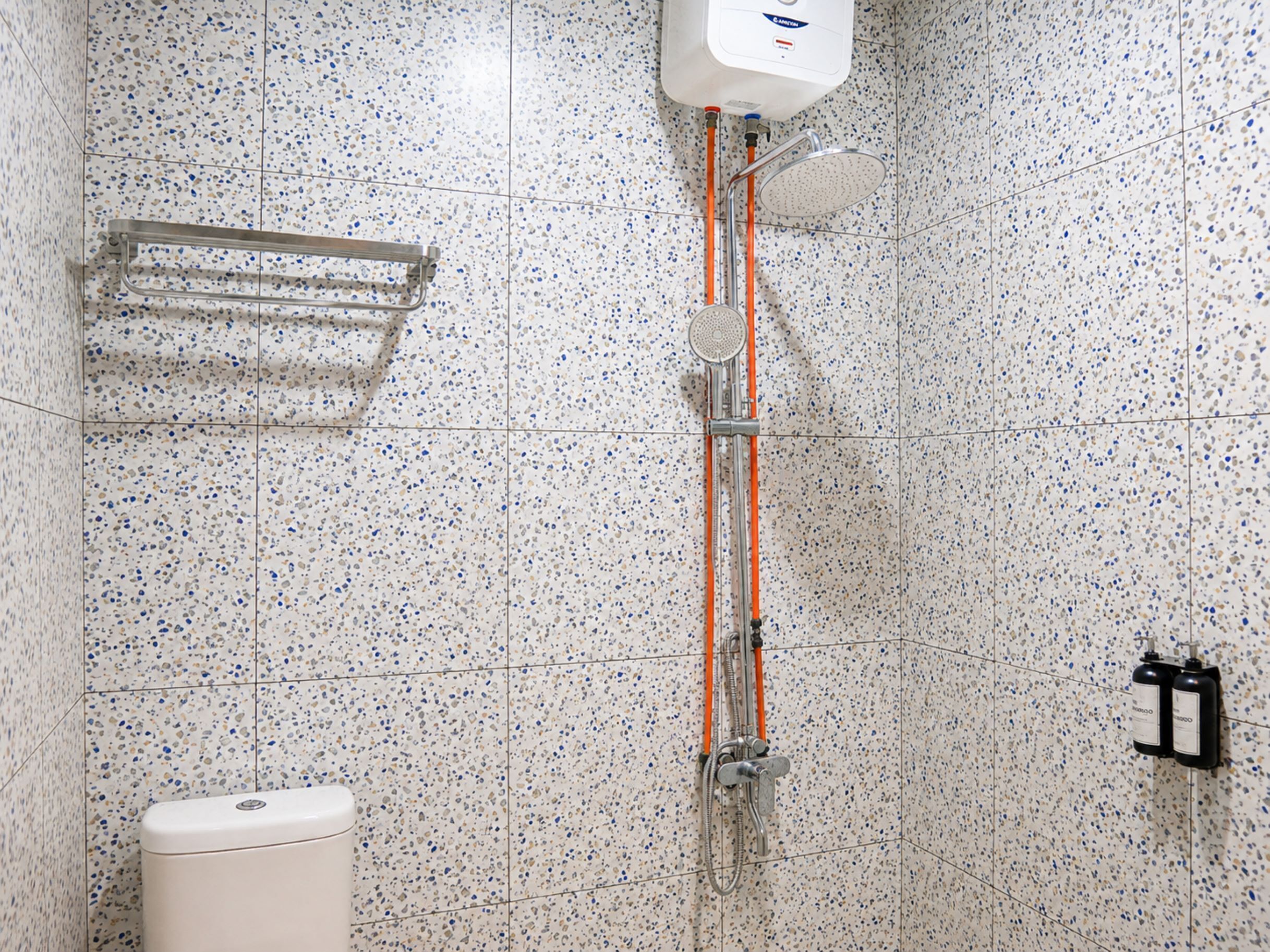 Une salle de bain équipée d’une douche, de toilettes et d’un distributeur de savon.