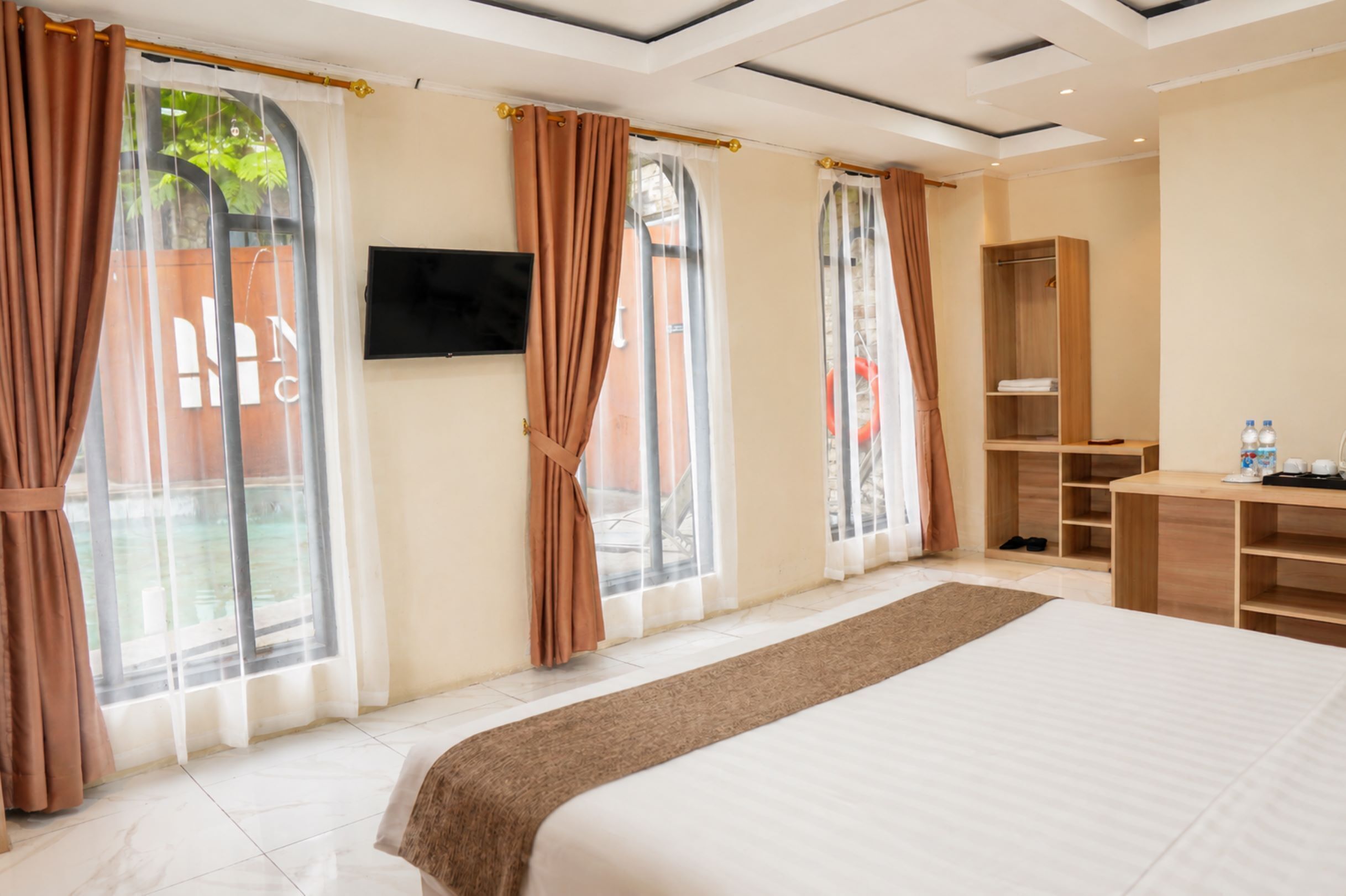 A hotel room with a large bed, a TV mounted on the wall, and a wardrobe.