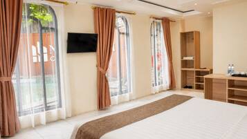 A hotel room with a large bed, a TV mounted on the wall, and a wardrobe.